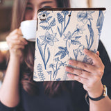 a girl is holding and viewing personalized iPad folio case with Flower design 